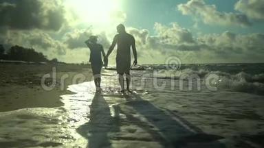 一位年轻的父亲和他的儿子沿着海滨散步。 阳光灿烂. 他们在说话。 家庭幸福。 <strong>信托</strong>基金